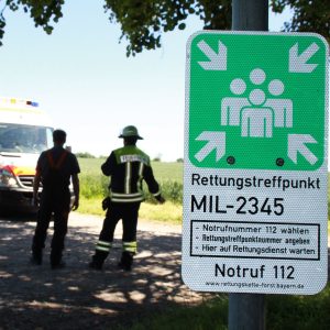 Hinter einem Schild für den Rettungspunkt stehen Rettungskräfte